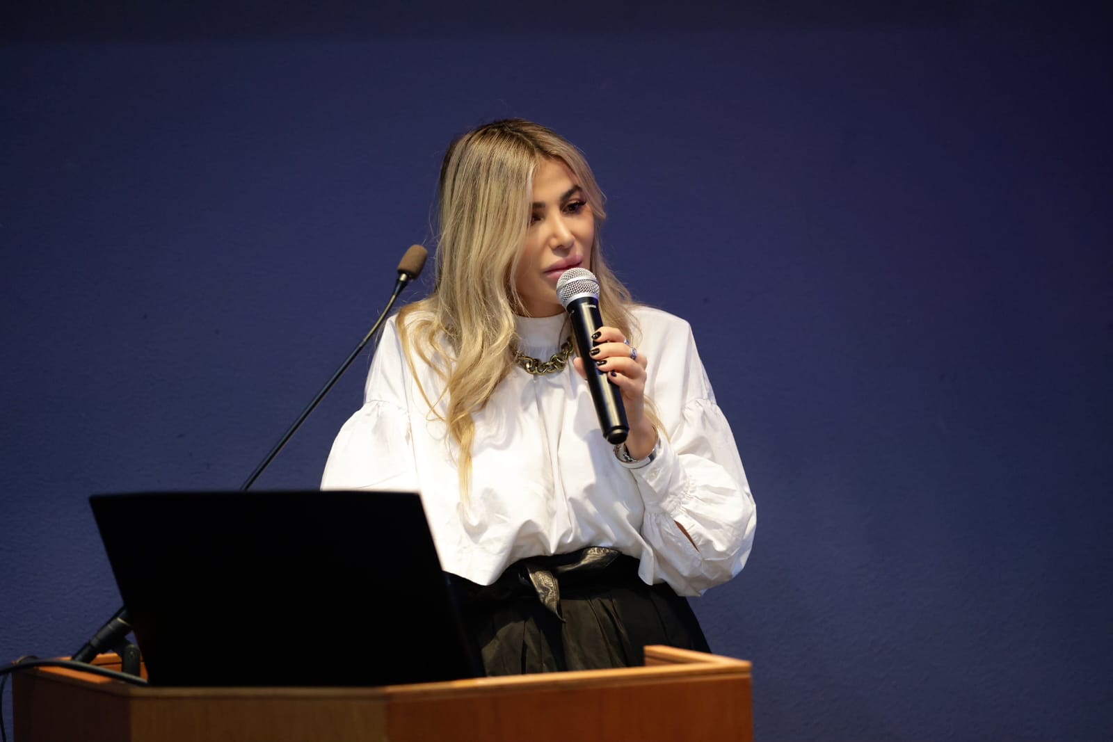 Rita Sarkis speaking — white shirt